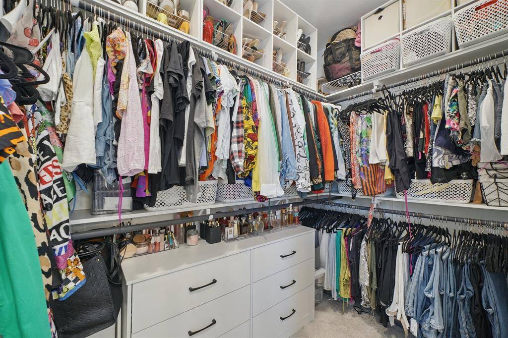 One of the spacious walk-in primary closet features built-in shelving, drawers, and ample hanging space, offering functional storage and organization throughout.