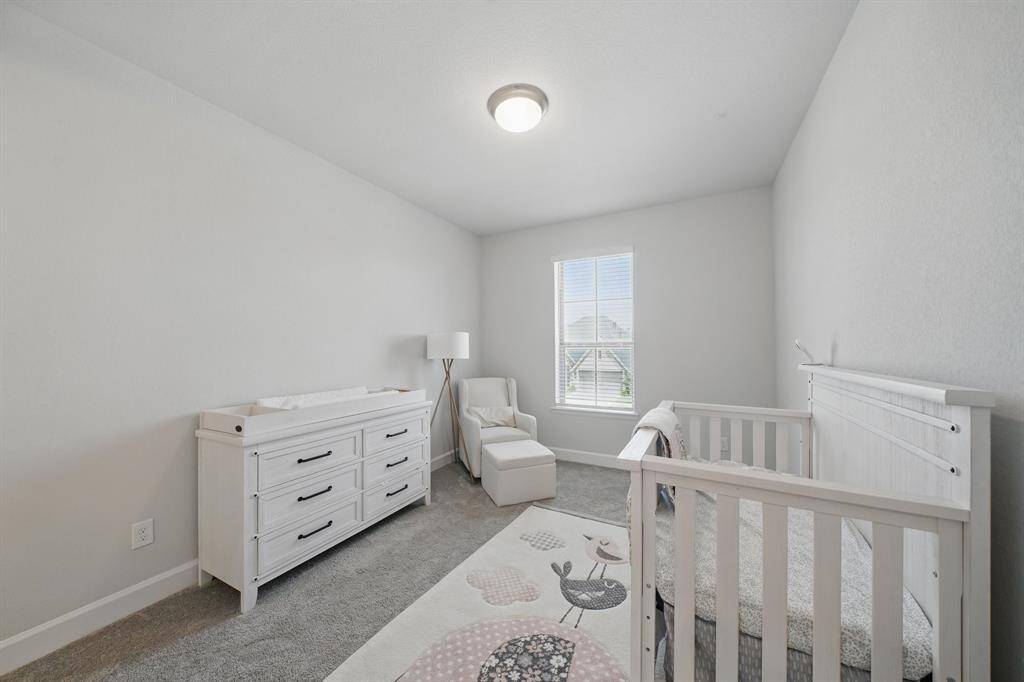 A spacious upstairs bedroom with neutral tones, soft carpet, and a large window—perfect for a nursery, guest suite, or additional family space.