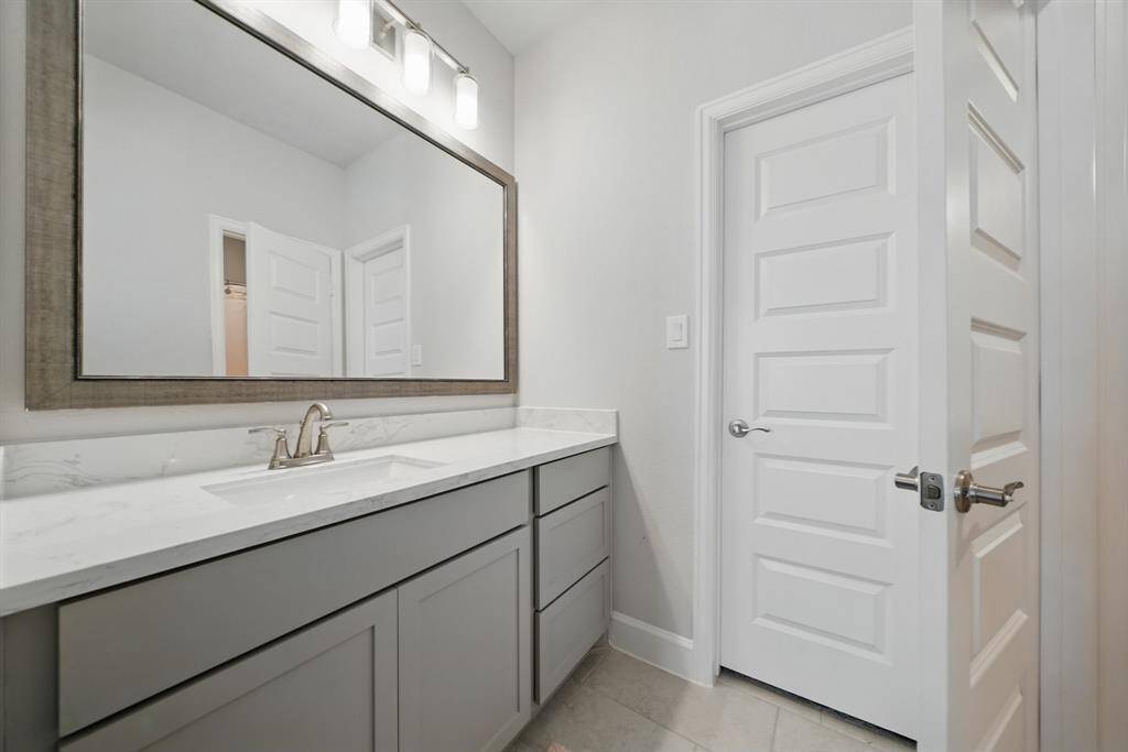 This Hollywood-style bathroom features a spacious vanity with framed mirror and a separate enclosed area for the toilet and shower, offering added privacy and functionality.