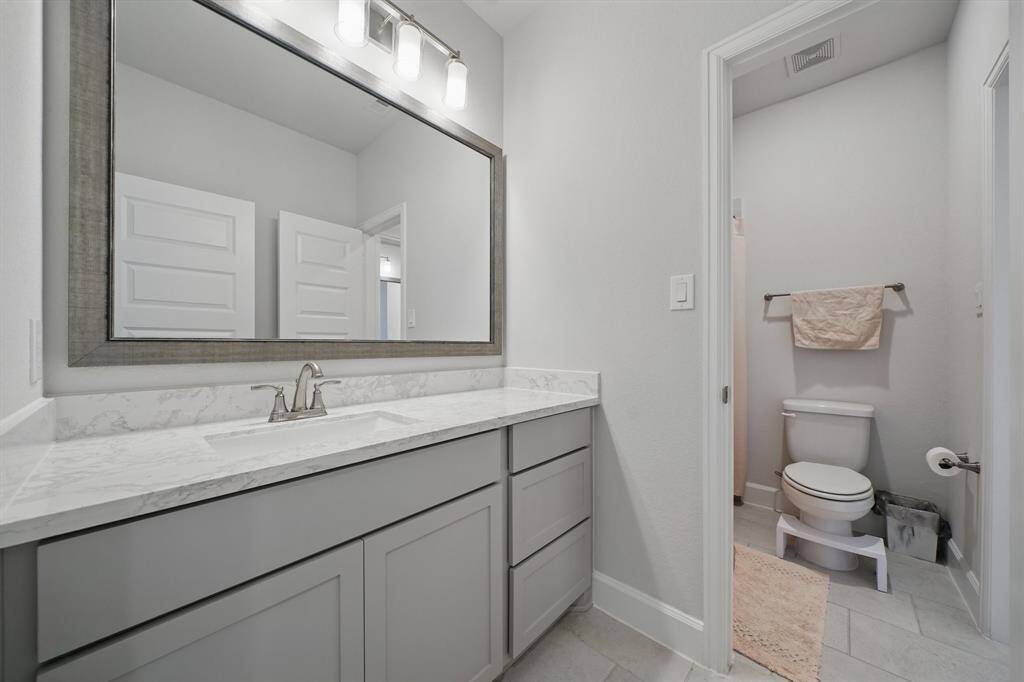 This Hollywood-style bathroom features a spacious vanity with framed mirror and a separate enclosed area for the toilet and shower, offering added privacy and functionality.