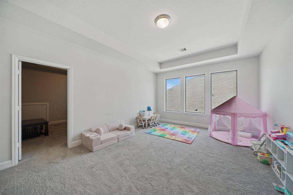 The upstairs game room offers flexible space with tray ceilings, natural light from triple windows, and ample room for play, study, or hobbies.