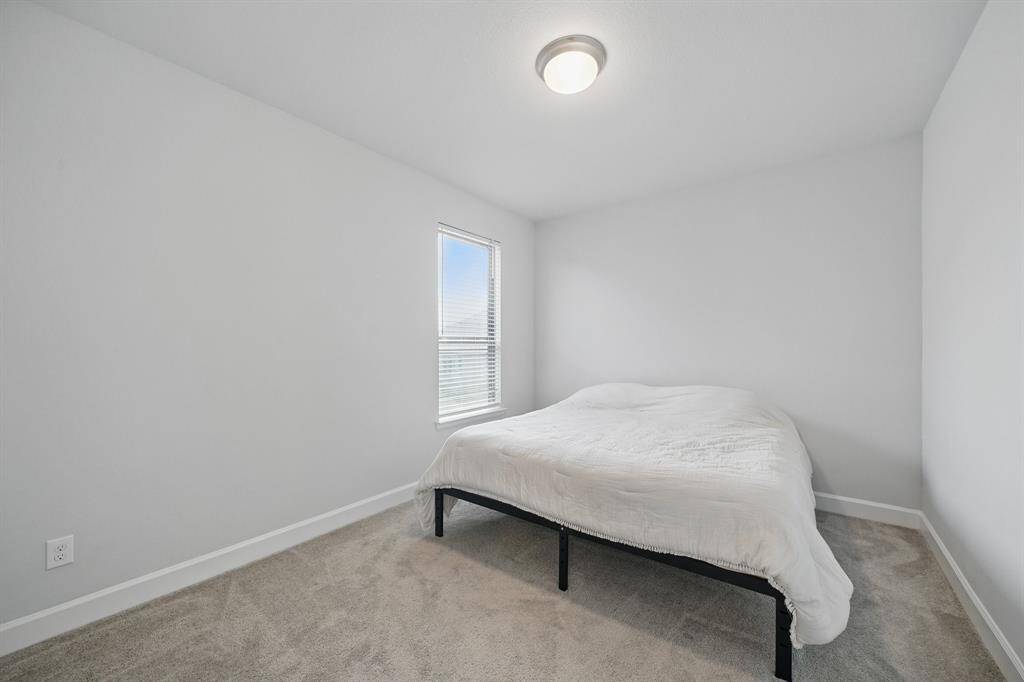 This secondary bedroom features plush carpet, a large window for natural light, and a neutral palette ready for your personal touch.