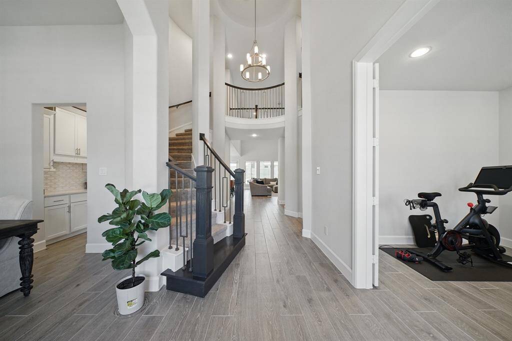 The soaring rotunda foyer features wood-look tile floors, a curved staircase with wrought iron spindles, and an open view into the main living areas. A private study with French doors sits just off the entry.
