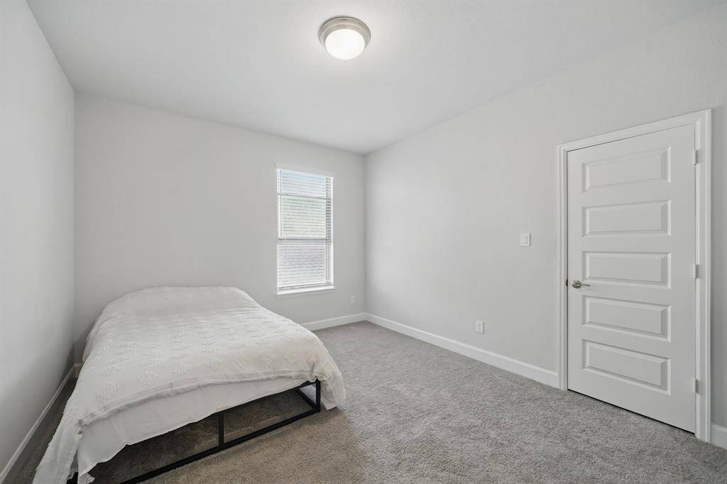 This secondary bedroom features plush carpet, a large window for natural light, and a neutral palette ready for your personal touch.