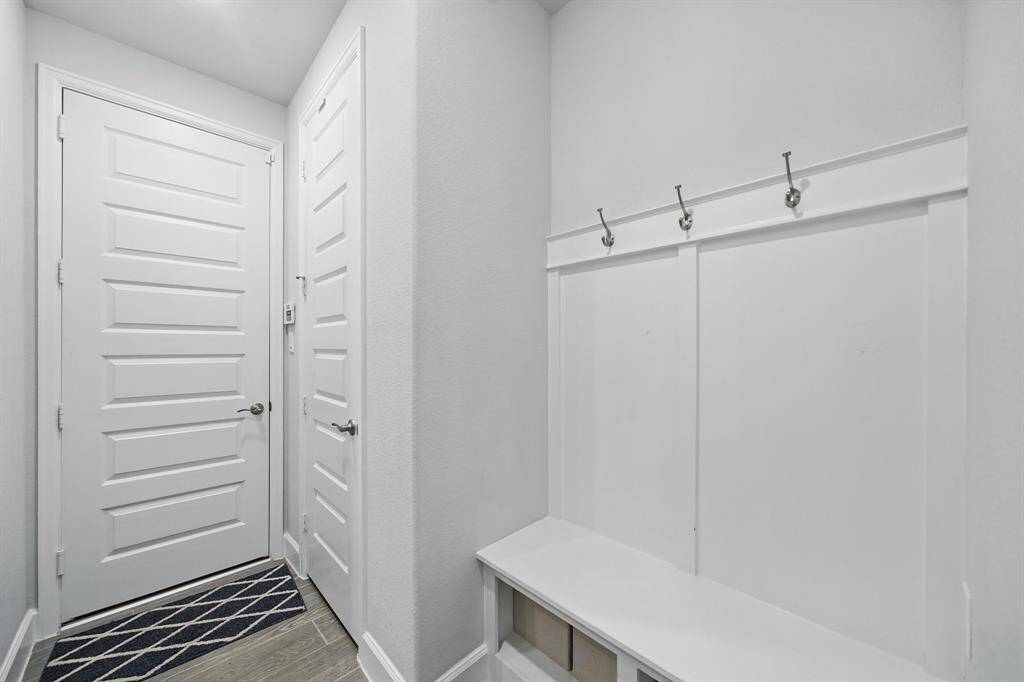 Mudroom area located near the garage and laundry room, complete with wall hooks and bench with cubby storage—ideal for organizing daily essentials.