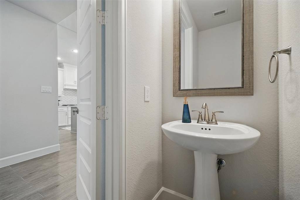 Conveniently located half bath on the first floor, featuring a pedestal sink and framed mirror—perfect for guests.