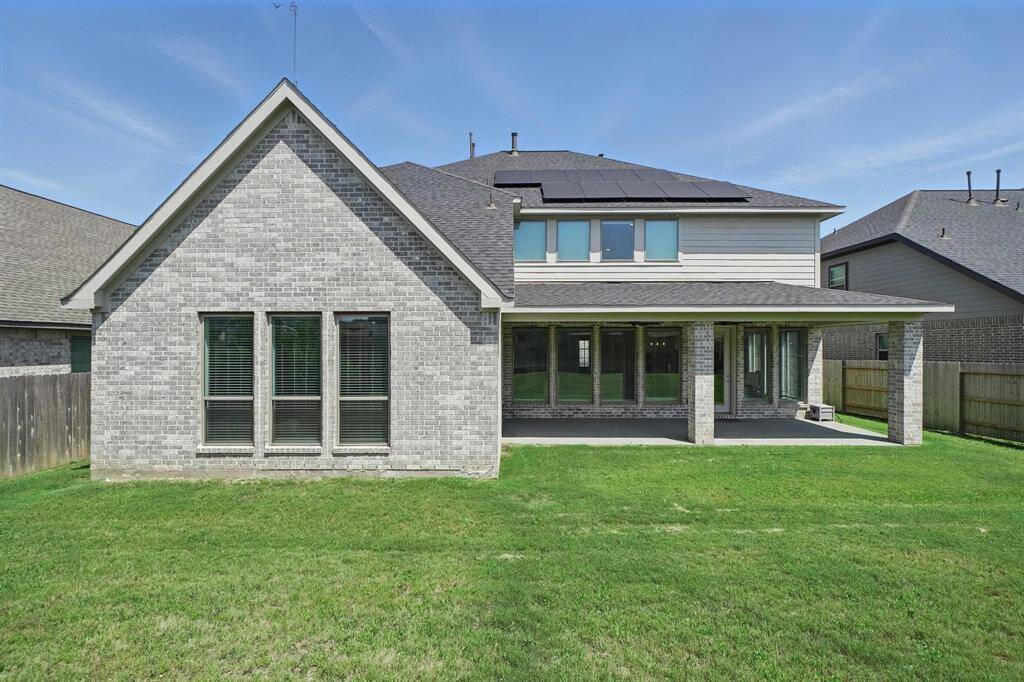 Rear elevation highlights the home’s brick façade, covered patio, and installed solar panels—offering both style and sustainability.