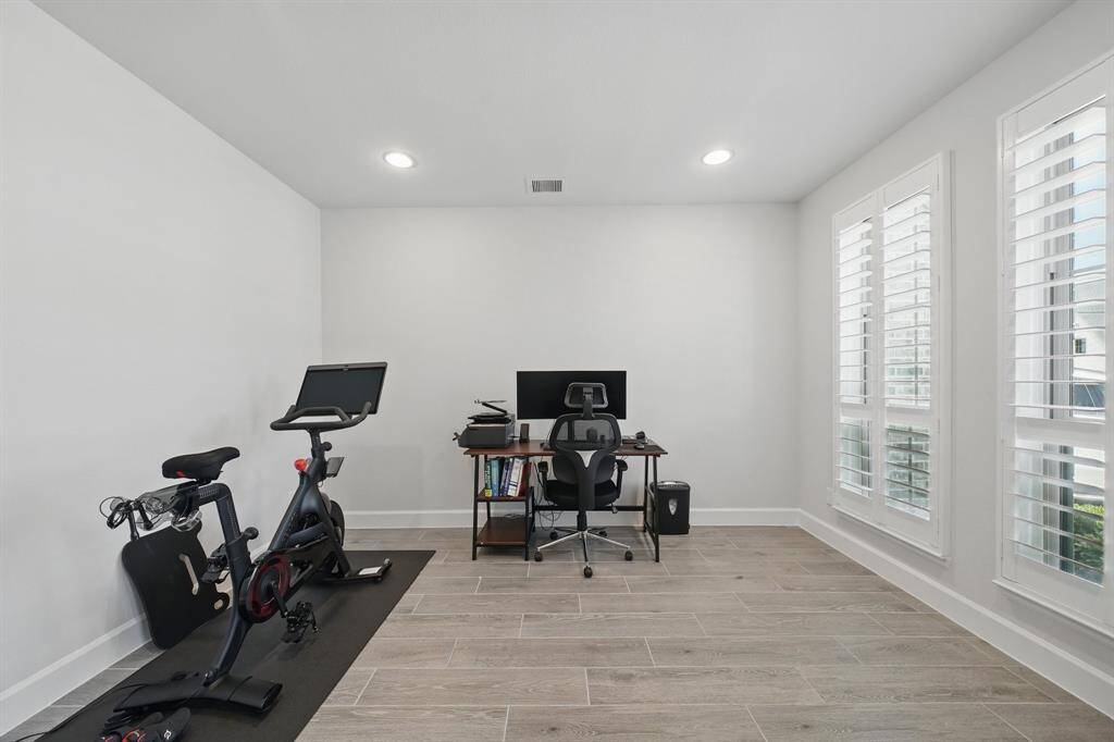 This versatile front-facing room includes plantation shutters, wood-look tile flooring, and space for a home office, gym, or study.