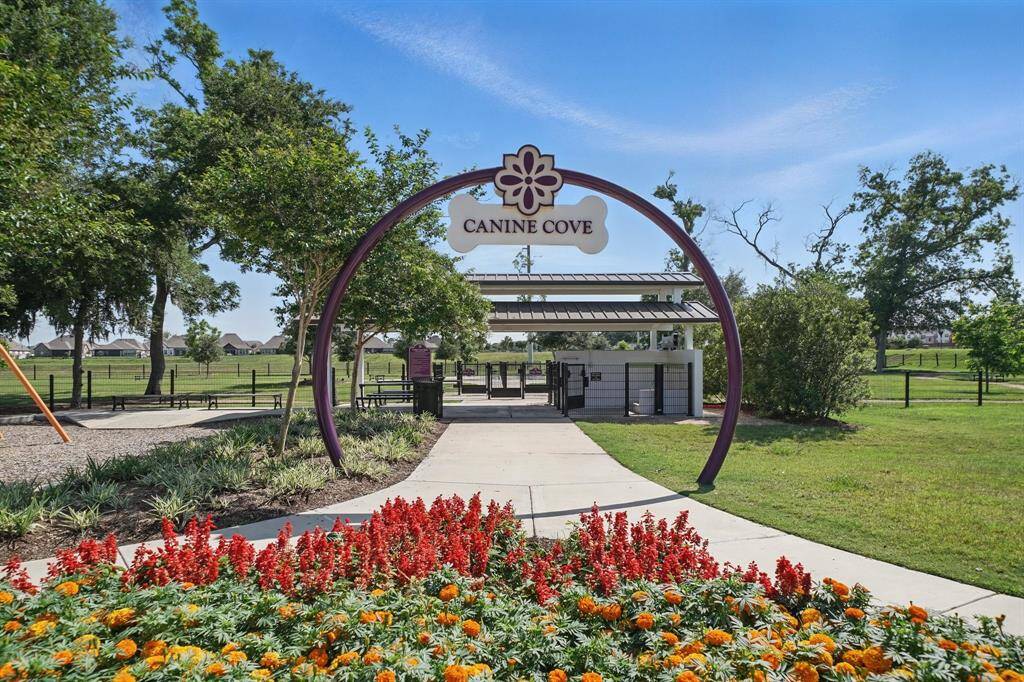 Charming entry to Canine Cove, a dedicated neighborhood dog park with beautifully landscaped walkways and a fenced-in play area for your pets to roam freely.