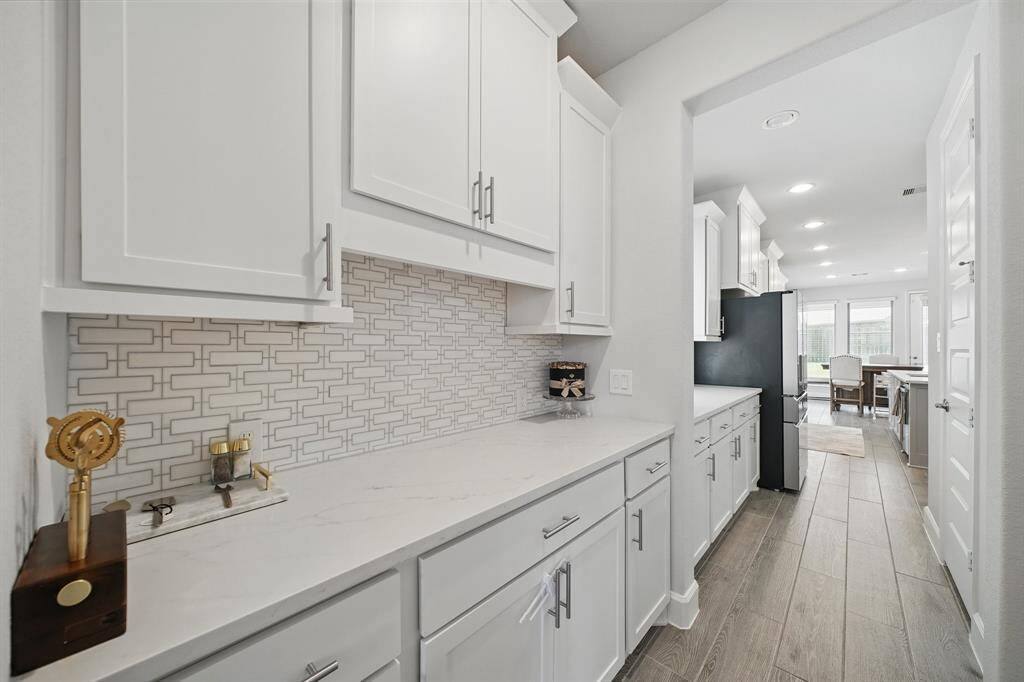 A spacious butler’s pantry offers extended countertop space, abundant cabinetry, and stylish backsplash—perfect for serving or storage between the kitchen and dining room.