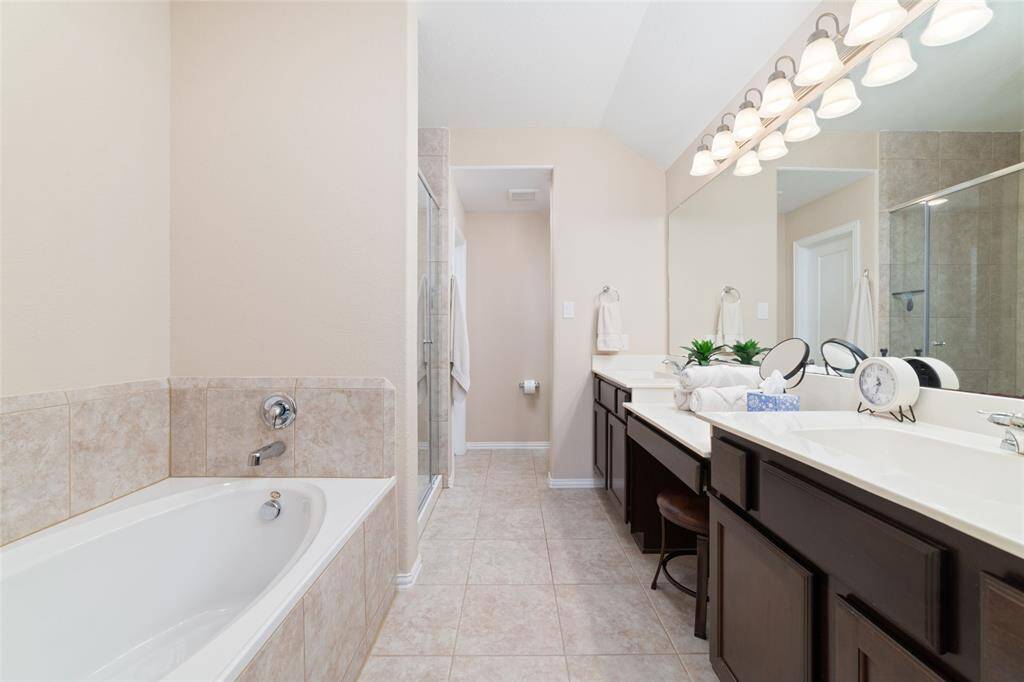 Primary bedroom suite with double sinks, soaking tub, separate shower, and large walk-in closet.