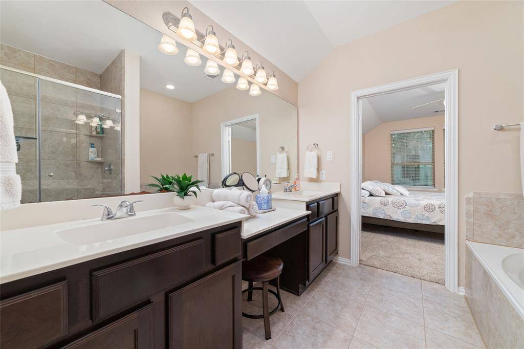 Primary bedroom suite with double sinks, soaking tub, separate shower, and large walk-in closet.