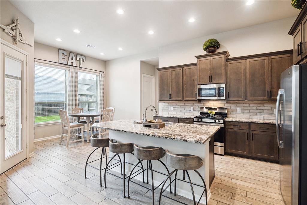 Modern kitchen with sleek wooden cabinets, granite countertops, and stainless steel appliances. Features a central island with room to sit and enjoy all your culinary masterpieces.
