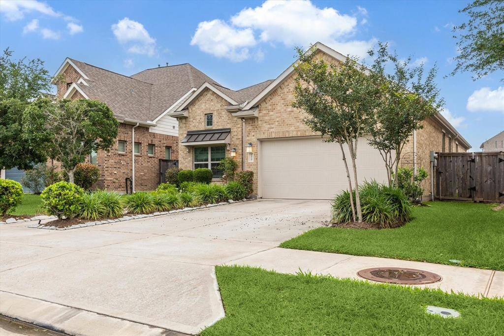 This is a charming single-story brick home with a well-maintained front yard and a two-car garage. The property features a landscaped garden with mature trees and shrubs, offering great curb appeal.