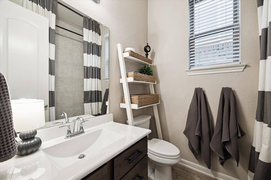 Modern bathroom featuring a sleek vanity with a polished faucet, ladder-style shelving with wicker baskets, and neutral decor.