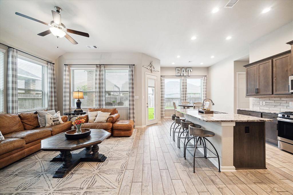 Inviting open-concept living area with abundant natural light from large windows, and a stylish kitchen with a spacious granite island and modern appliances. Perfect for entertaining or relaxing.