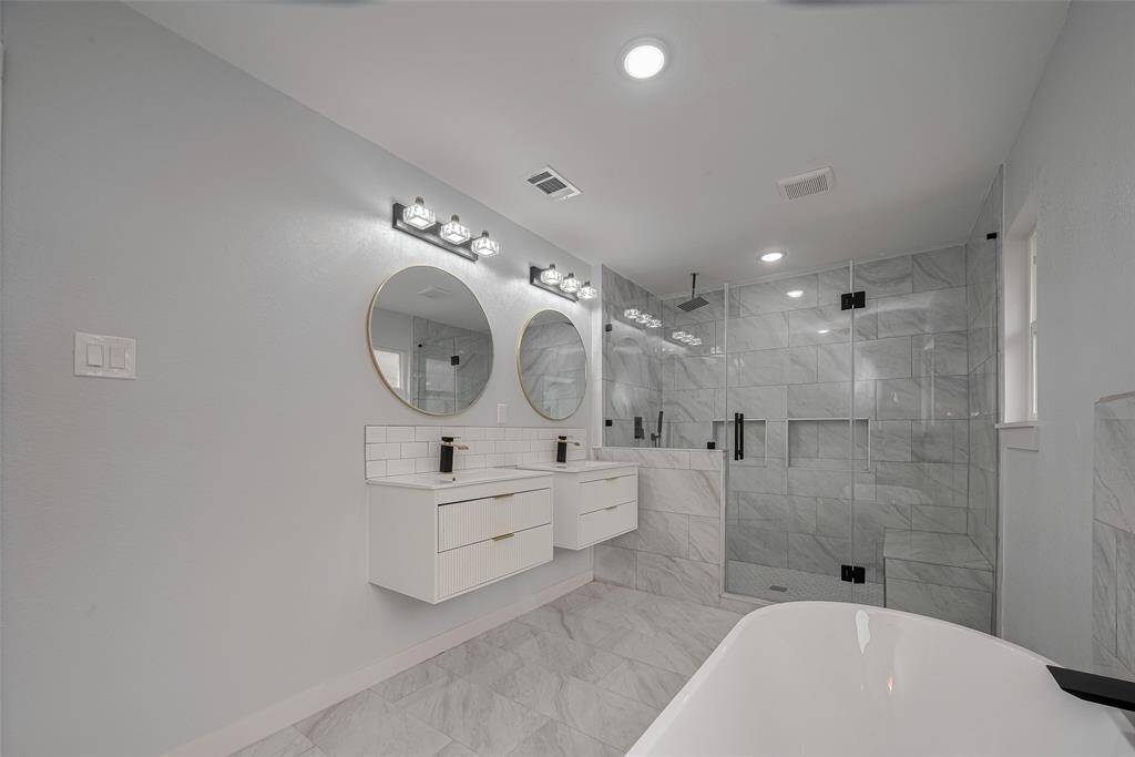 Wall hanging modern vanities with two sinks with frameless shower glass and range shower.