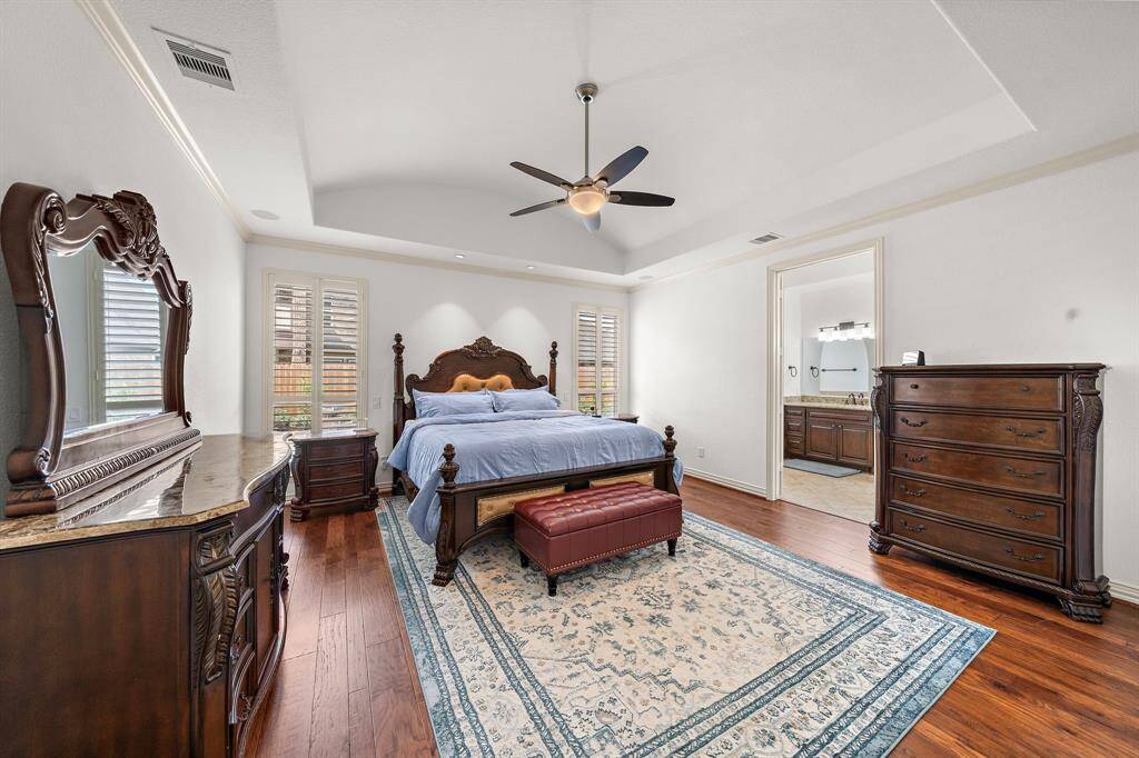 The primary bedroom boasts custom lighting, gorgeous plantation shutters, in-ceiling speakers, and deep wood flooring