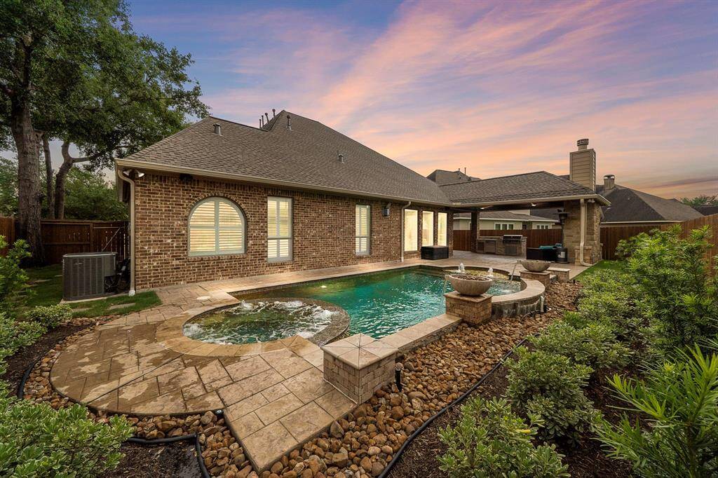 Lush greenery surround a beautiful and symmetrical pool with gorgeous spa. The fountains add an extra layer of design. Enjoy cooking outside in your second kitchen while watching your favorite sports team on the tv mounted above the outdoor fireplace. In the colder months, curl up next to the fireplace and enjoy the fire.