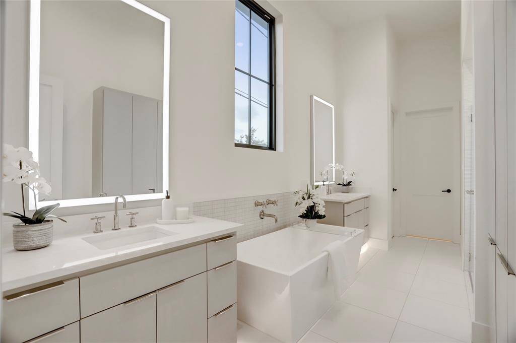 The primary bathroom also features toe kick lighting under each vanity, a large soaking tub, separate shower, built-in linen/medicine storage, and leads to a dream closet.