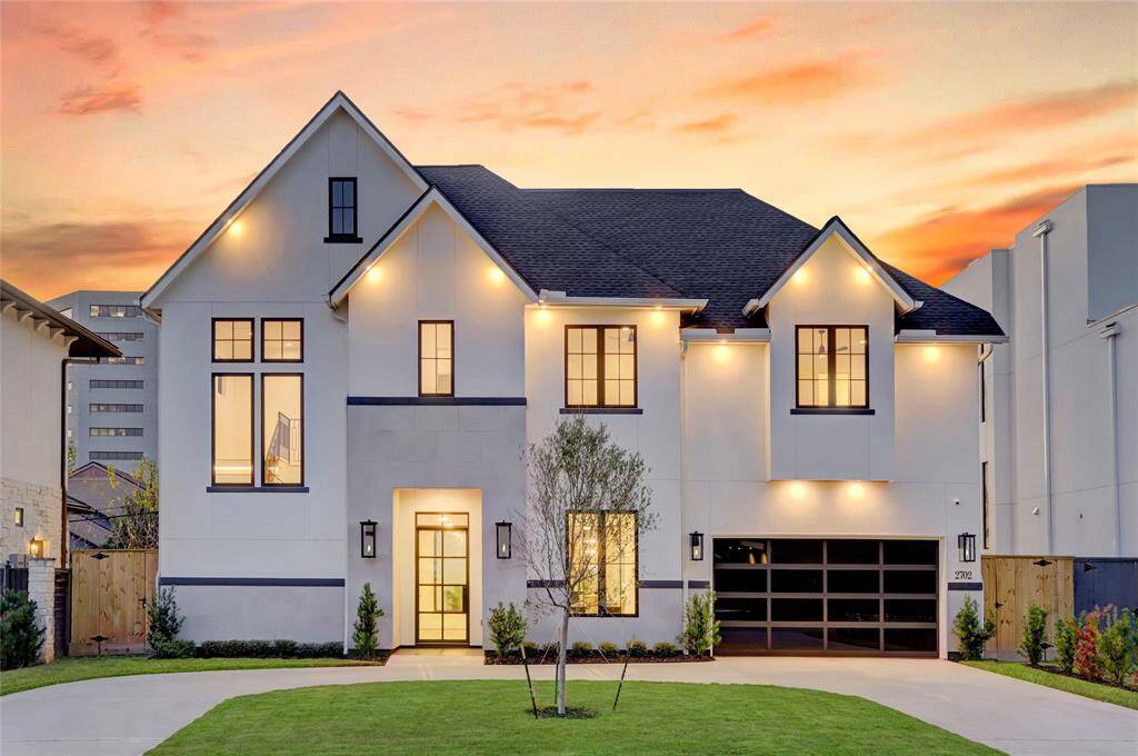 The front elevation is absolutely stunning and features accent lighting, four gas lamps, and tinted glass garage door that offers a modern touch with privacy.