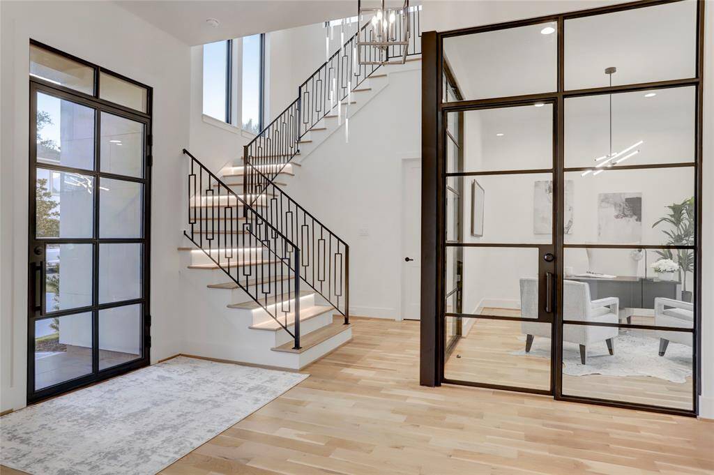 The metal door, glass corner study, and stair railing add to the transitional feel of the home.
