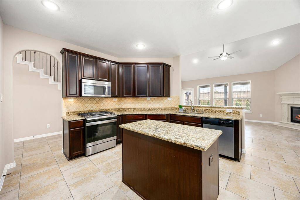 The neutral toned kitchen offers a functional island and granite counters with access to the living room.
