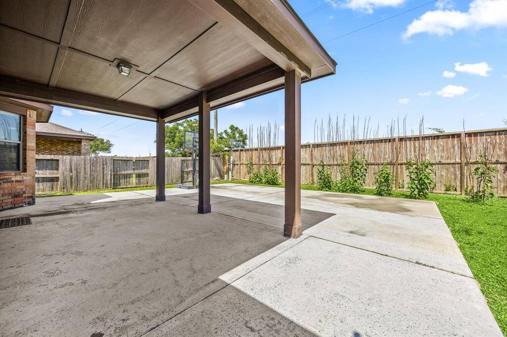 Large backyard features a large covered patio and an extension that was being used for basketball.