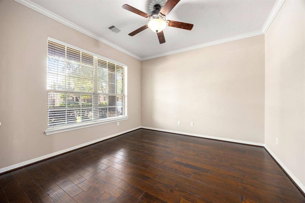 Front room study is complemented by crown molding, a ceiling fan, French doors at the entry, and a view of the freshly landscaped front yard.