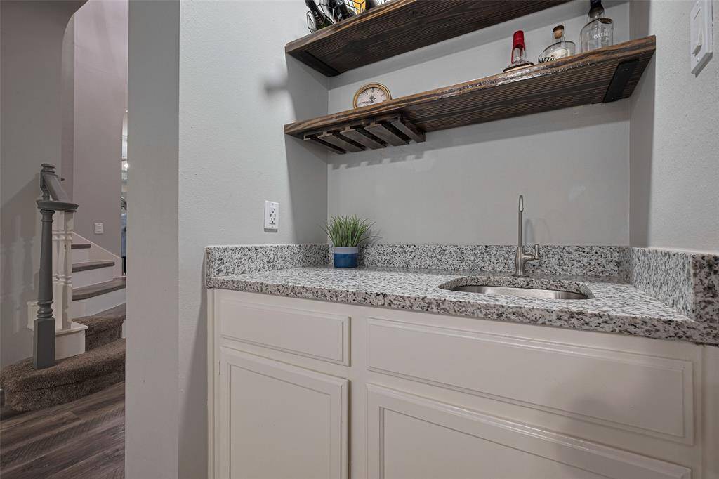 This stylish wet bar features a sleek granite countertop, built-in shelving, and a wine glass rack—perfect for entertaining with ease and elegance.