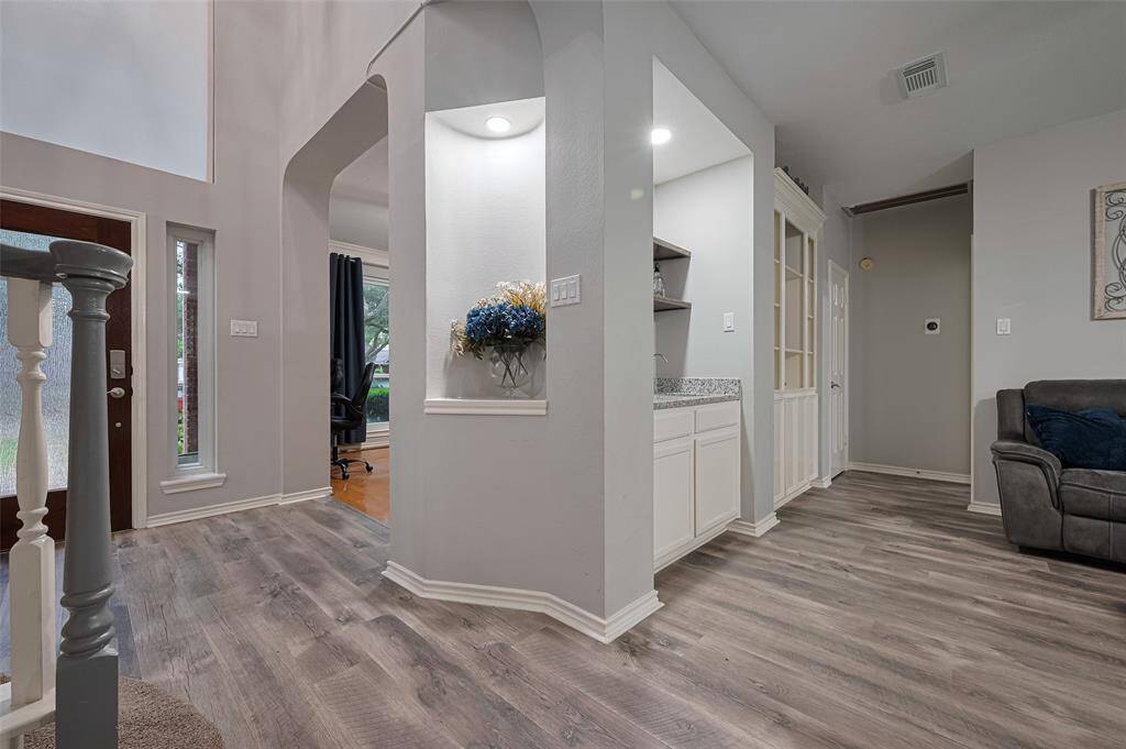 This photo highlights some of the special details of the home - the lighted art niche, the arched entry to the home office and on the wall is the wet bar and just beyond the wet bar is another built-in bookcase area.