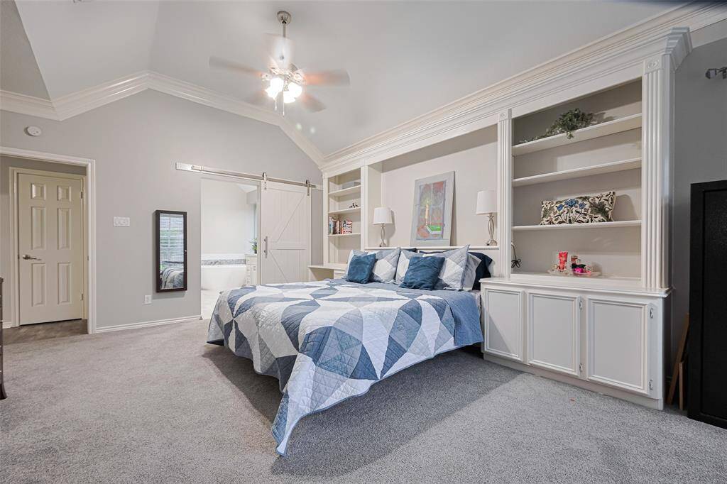Nestled under a striking coffered ceiling, a sliding barn door leads to the luxurious en-suite bathroom, blending charm and modern convenience.