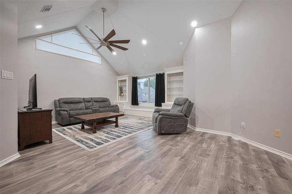 The upstairs gameroom features recent engineered wood flooring, a cozy sitting area, and built-in bookshelves flanking a charming window seat—perfect for relaxing, reading, or entertaining.