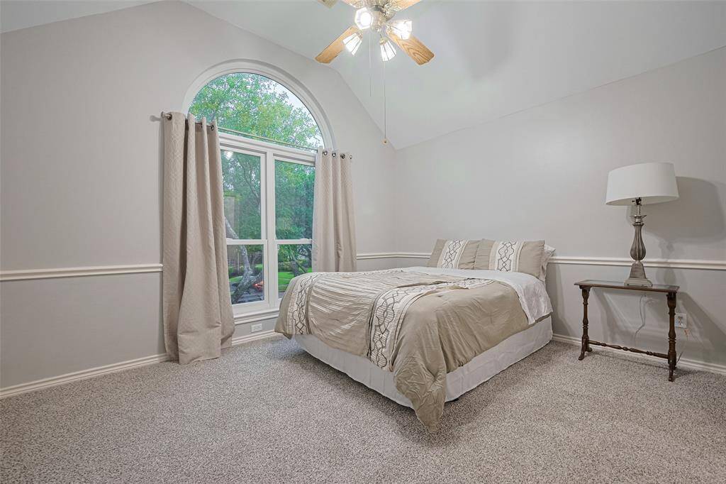 This inviting guest bedroom offers ultimate comfort with its en-suite bathroom, coffered ceilings, new carpet, and a beautiful arched window, all accented by classic chair railing for added charm. This is a queen size bed so you can see how spacious this room is.