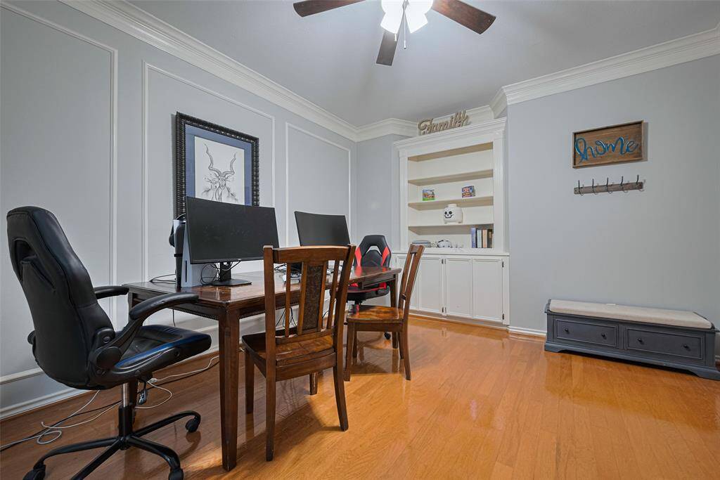 To the left of the entry is the actual home office, also with traditional wood flooring. Custom details include the built-in cabinets and shelving, the box molding on the wall to the left and the deep crown molding