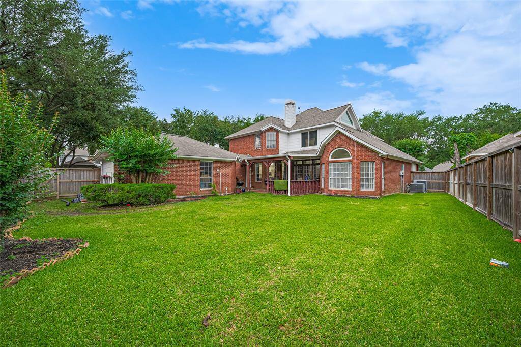 The spacious backyard offers plenty of room for play, gardening, or outdoor entertaining, with a clear view of the home's charming exterior and extended patio area.