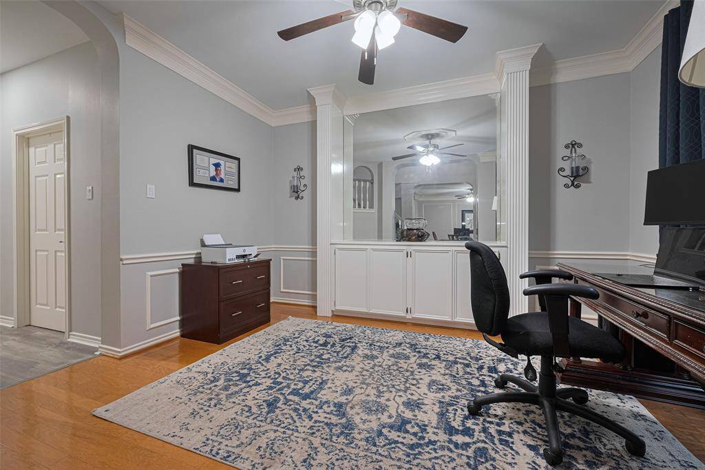 The formal dining, now being used as a home office, offers lots of natural light. Features include the built-in mirrored serving area with extra storage, Box molding on the walls & the stylish double crown molding.