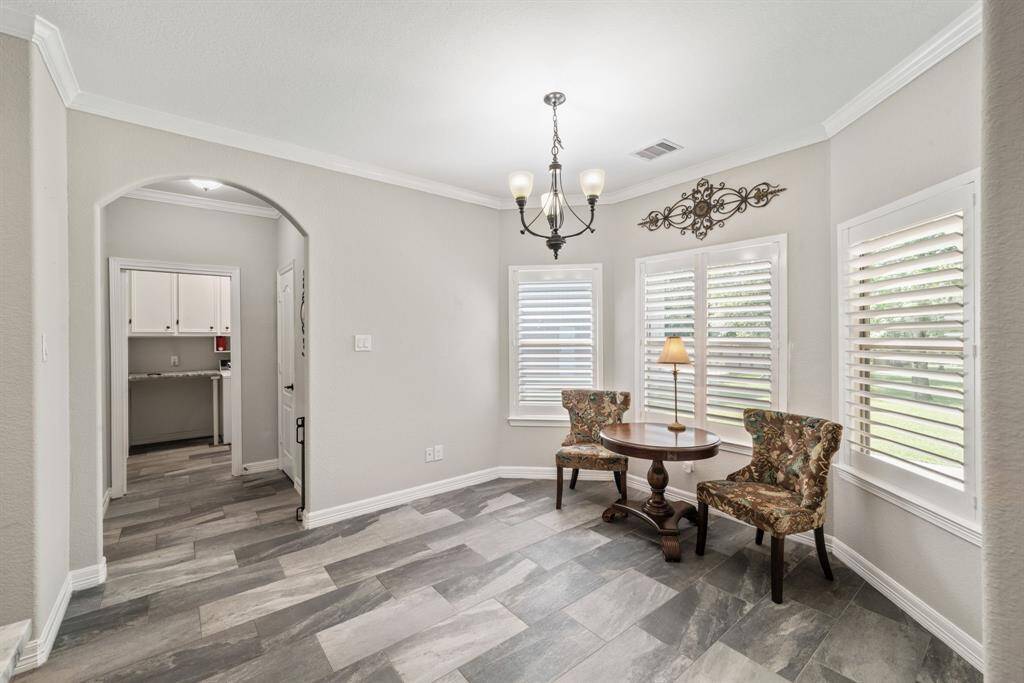 This charming nook beside the kitchen features a wall of curved windows that pour in natural light—an inviting spot for morning coffee.