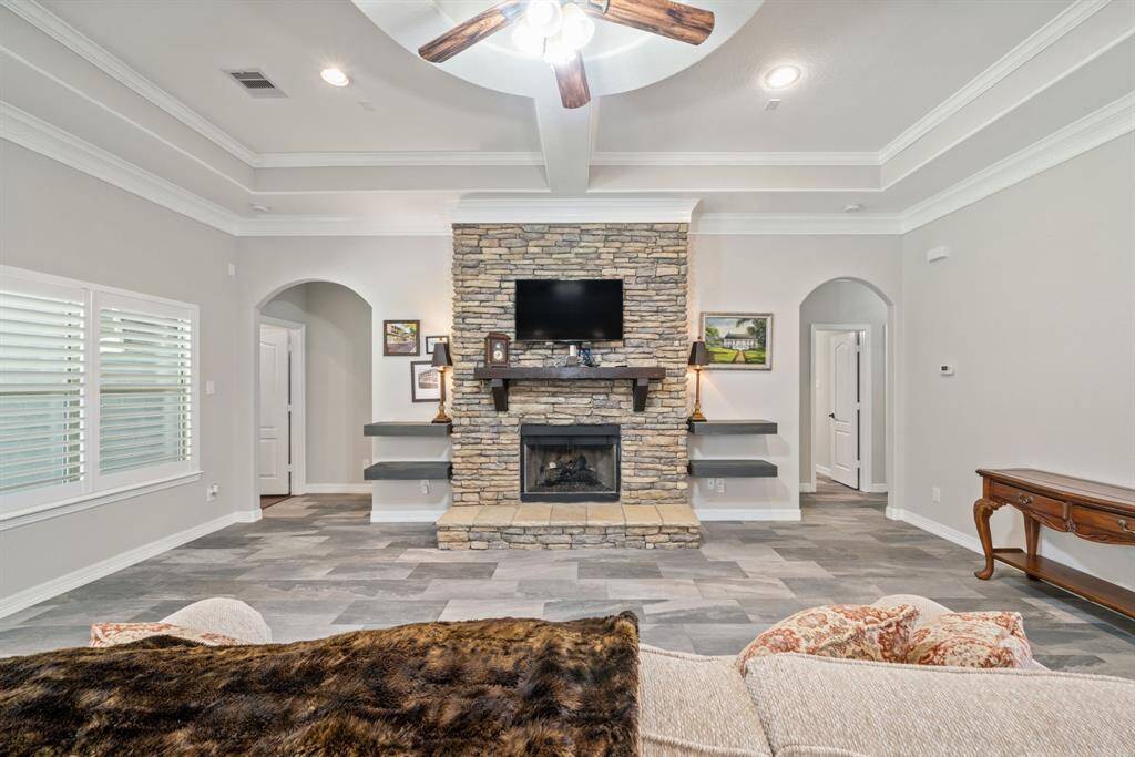 The living area is anchored by a dramatic floor-to-ceiling fireplace and grounded by beautifully tiled flooring, offering both warmth and elegance.