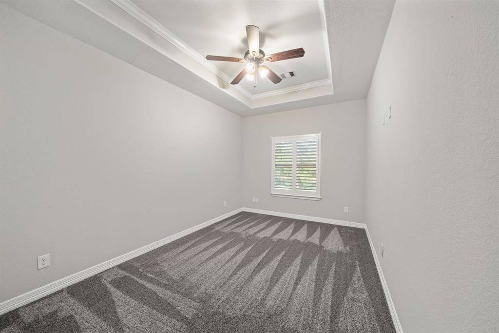Plush carpeting, a large window, and a recessed ceiling create a serene and inviting atmosphere in this bedroom.