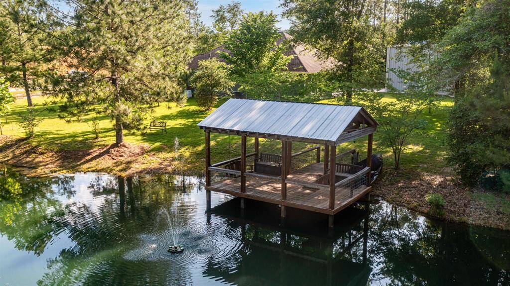 The pier stretches over the calm water, with the home peeking through the trees—capturing a perfectly framed rustic scene.