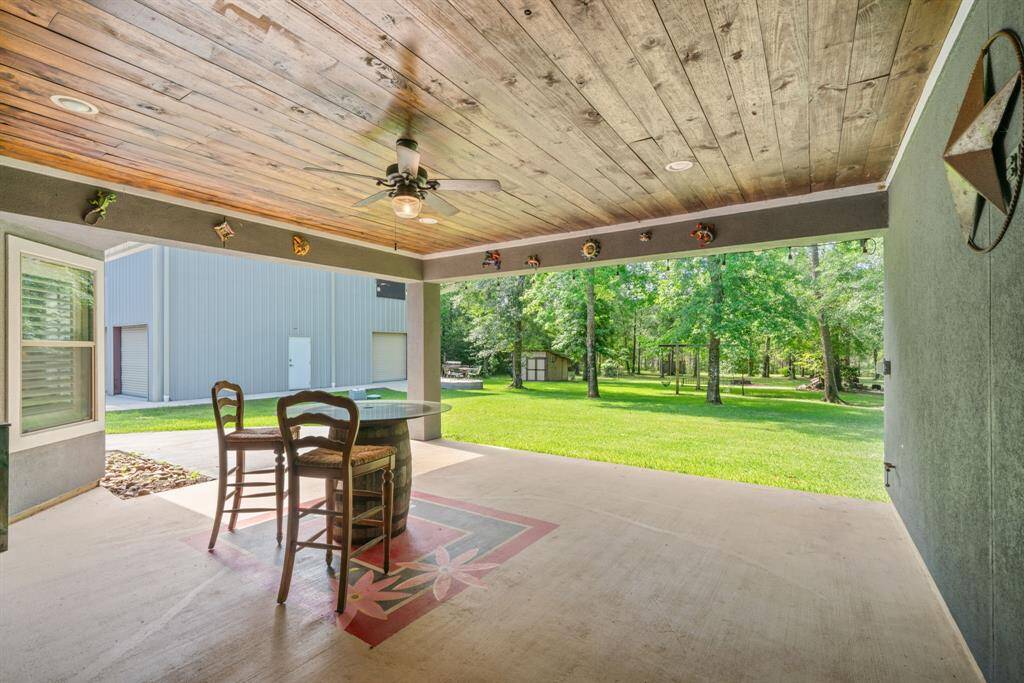 The covered patio extends from the rear of the home, featuring a wood-paneled ceiling and sweeping views of the backyard.