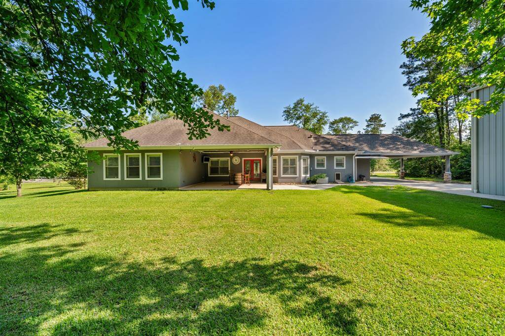 From the backyard, the home reveals a covered patio and elegant porte cochere, all nestled within lush surroundings for effortless outdoor living.