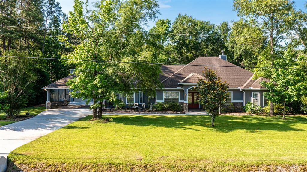 The smooth, long driveway winds past a sweeping green lawn, reinforcing the home’s grandeur and inviting presence.