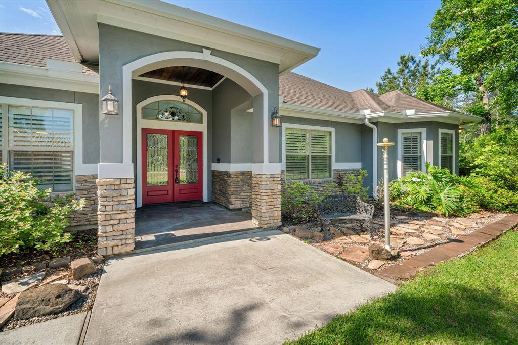 An elegant wide archway and dual sconce lights frame the vibrant red double doors, setting a bold and welcoming tone at the entry.