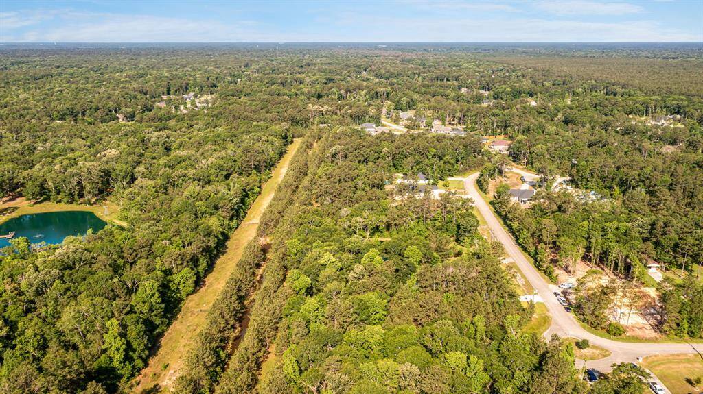 The pond glimmers in the background of this aerial, perfectly positioned within the natural rhythm of the property.