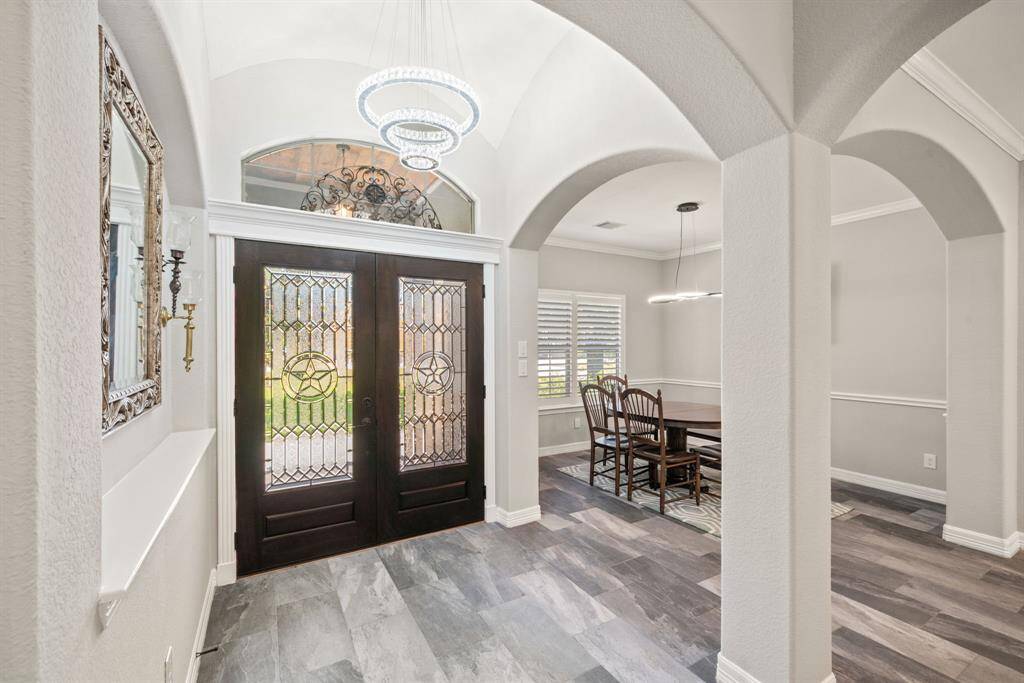 The entryway is bright, framed by graceful archways and topped with a transom window above the glass-paneled doors.