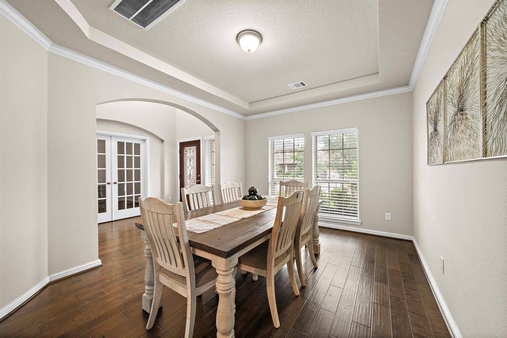 The formal dining room is located at the entry way of the home featuring tray ceilings, crown molding, and engineered hardwood floors.