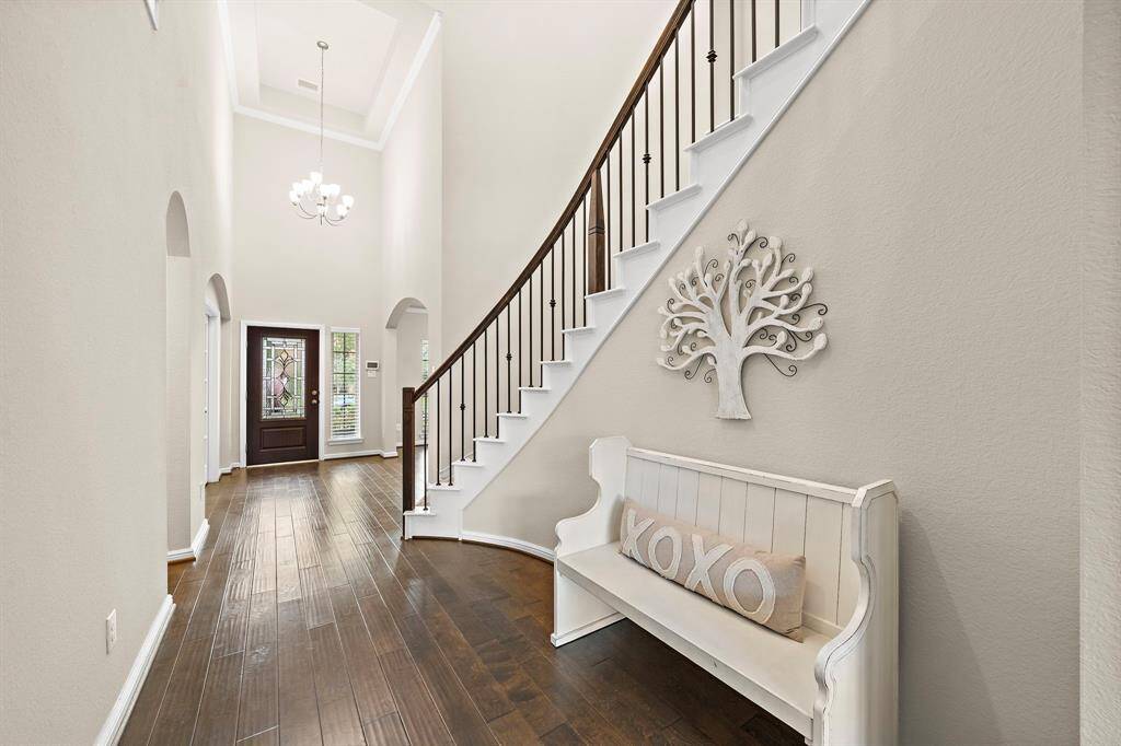 A look back at the foyer area featuring crown molding and a large chandelier.