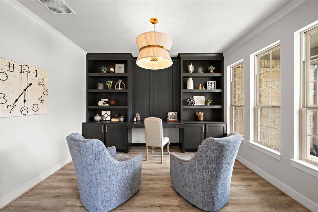 Gorgeous office located at the entryway of the homefeatures custom built-in shelving and cabinets, crown molding, and luxury vinyl plank floors.
